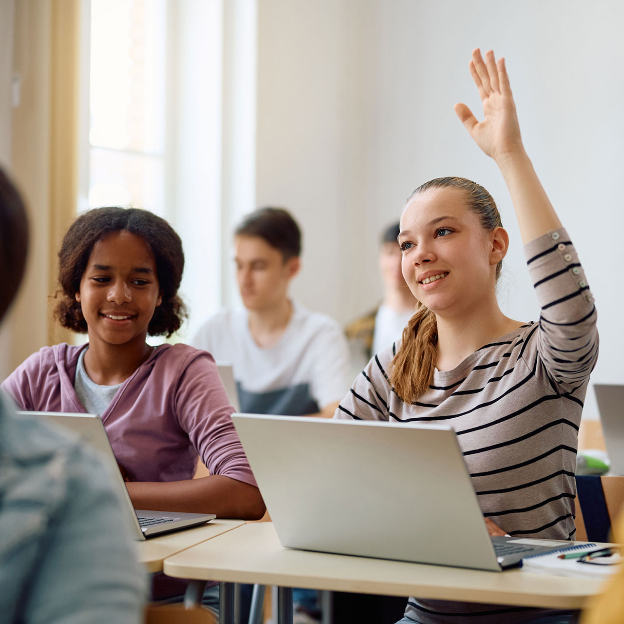 Une élève léve la main pour poser une question à l'enseignante ou enseignant.