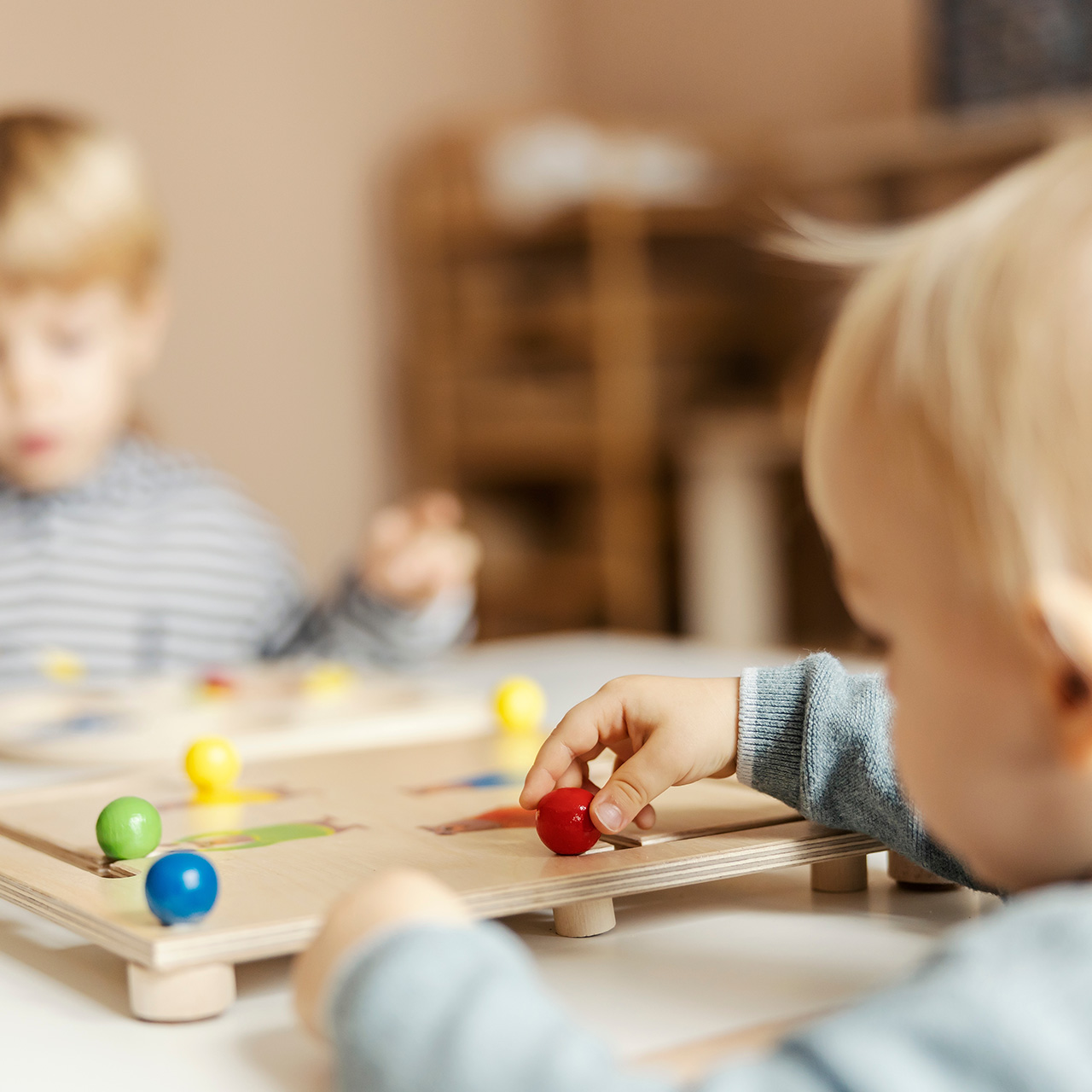 Une enseignante est accroupie pour expliquer à un jeune élève le contenu d'un livre.