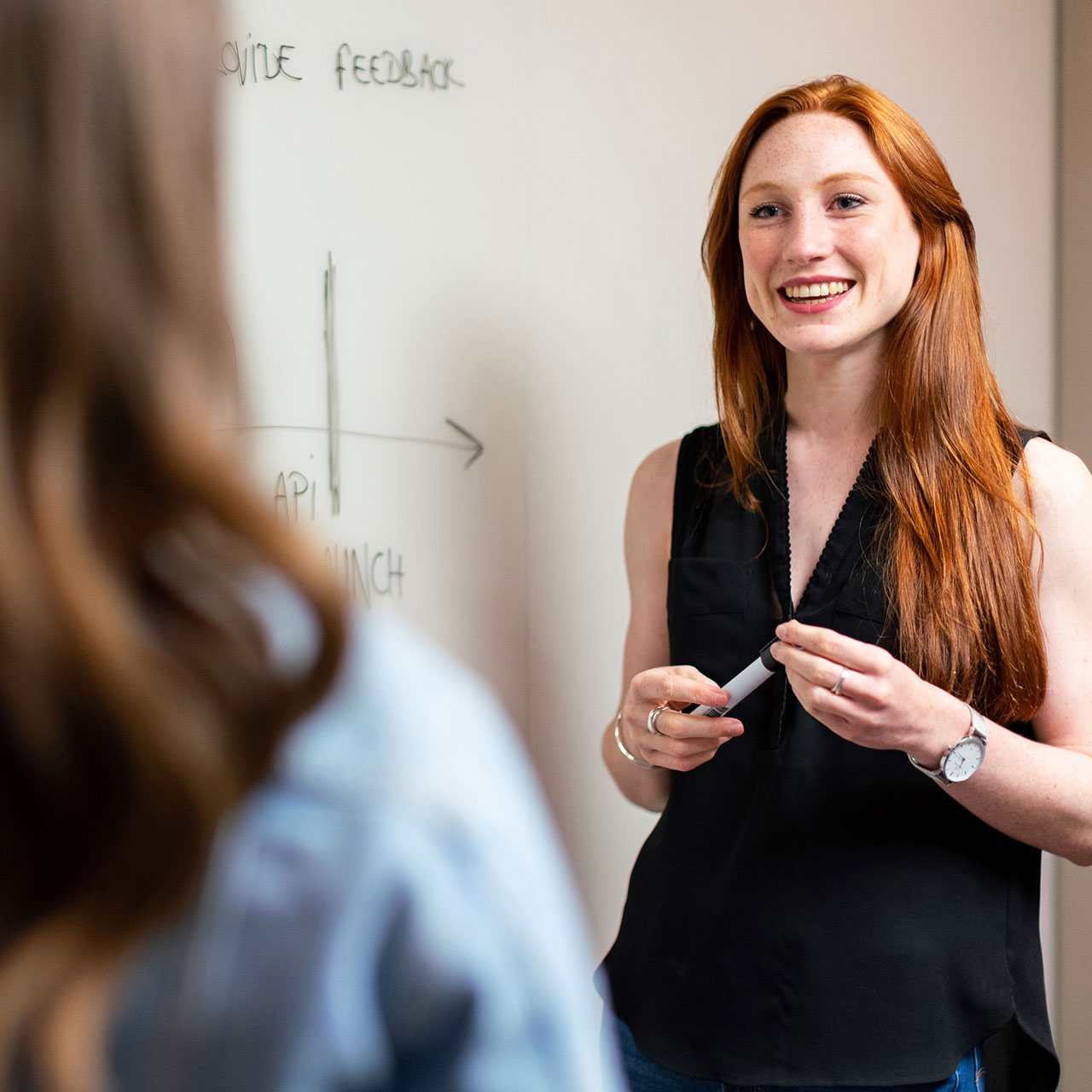 Une enseignante est en train d'apprendre à ses élève à l'aide d'un tableau de classe.